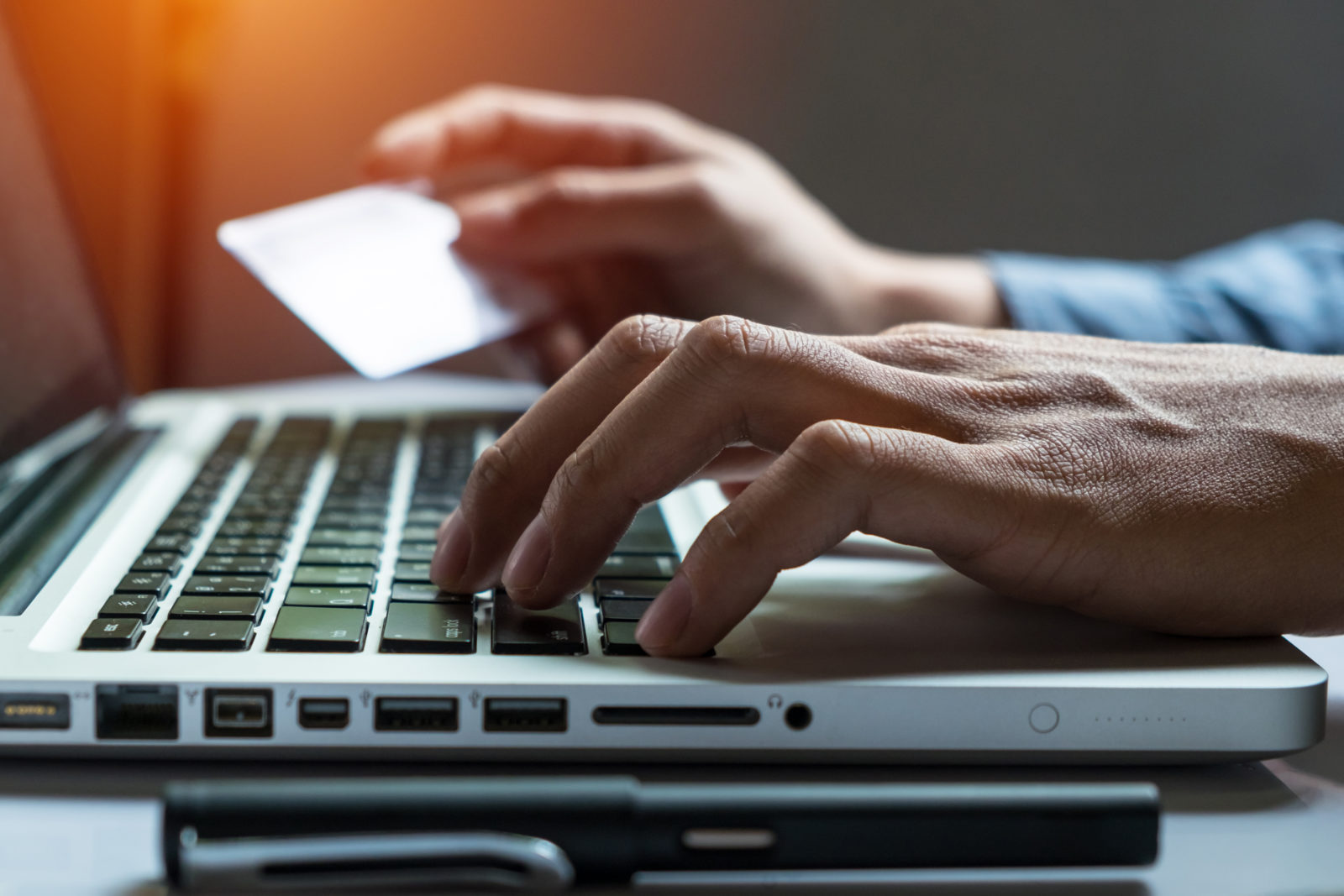 Man holding credit card in hand and entering security code using